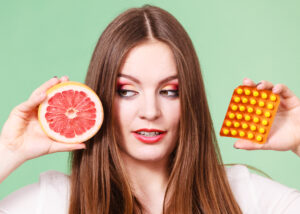 health advice myths- Woman holding fresh orange and Vitamin C tablets