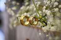 Close-up of shimmering gold wedding bands delicately resting on baby's breath flowers, symbolizing love and commitment.